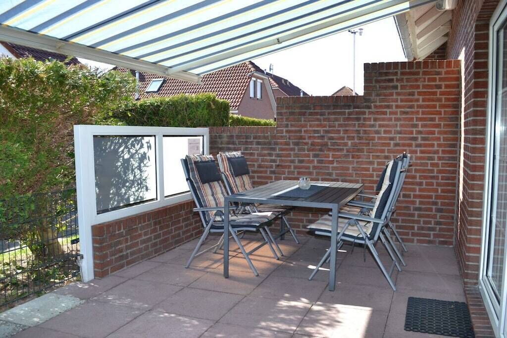 Une terrasse avec une table et des chaises, une véranda et un mur en briques.
