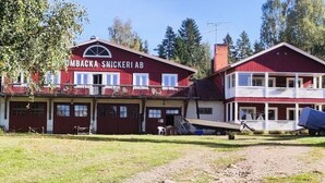 A two-story building with a red facade, a balcony on the upper floor, and a sign that reads 'OMBACKA SNICKERI AB'. - B and B in Bjuråker with swimming pool (Bjuråker)