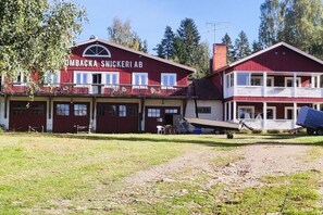 A two-story building with a red facade, a balcony on the upper floor, and a sign that reads 'OMBACKA SNICKERI AB'.