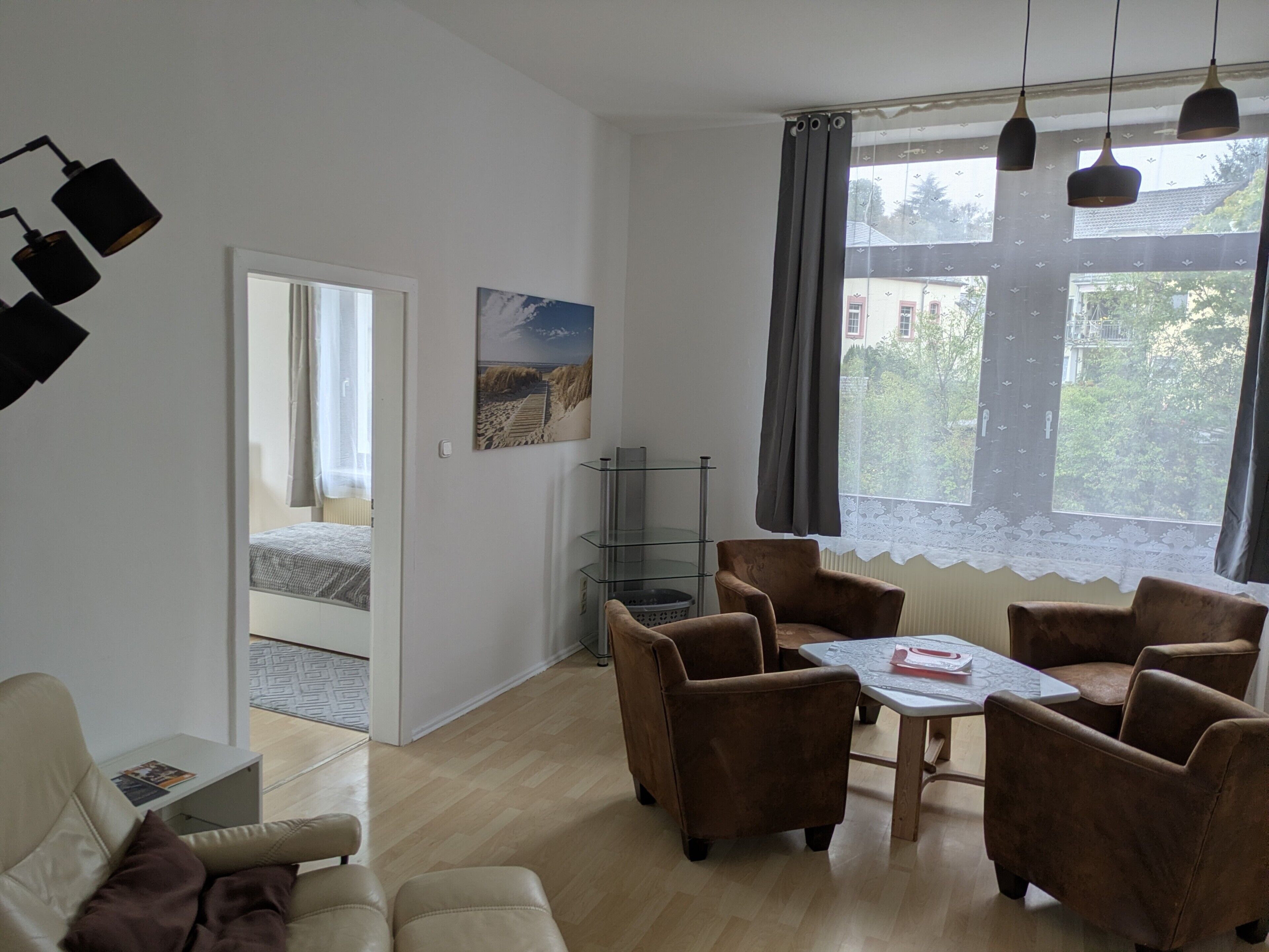 A room with a bed, a desk, a chair, a table, and a window with curtains.