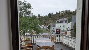 Ein Balkon mit Tisch und Stühlen, der auf einen Wohnbereich mit Häusern und Bäumen blickt.