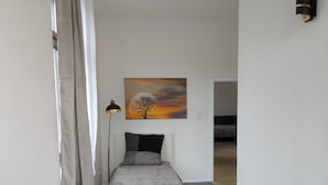 Ein kleines, modernes Schlafzimmer mit Bett, Nachttisch, Lampe und einem Bild an der Wand.