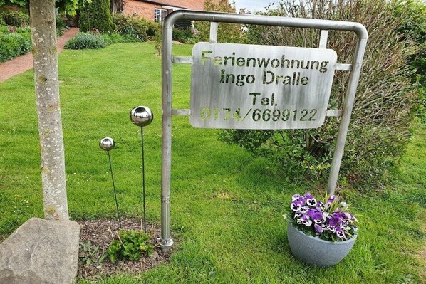 Een metalen bord met de tekst die een eigendom aangeeft genaamd 'Ferienwohnung Ingo Dralle' en een telefoonnummer.