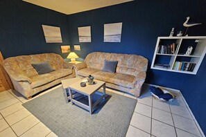 A living room with two sofas, a coffee table, a bookshelf, and wall art. - Anke Dralle Strandweg 11 (Elbinsel Krautsand)