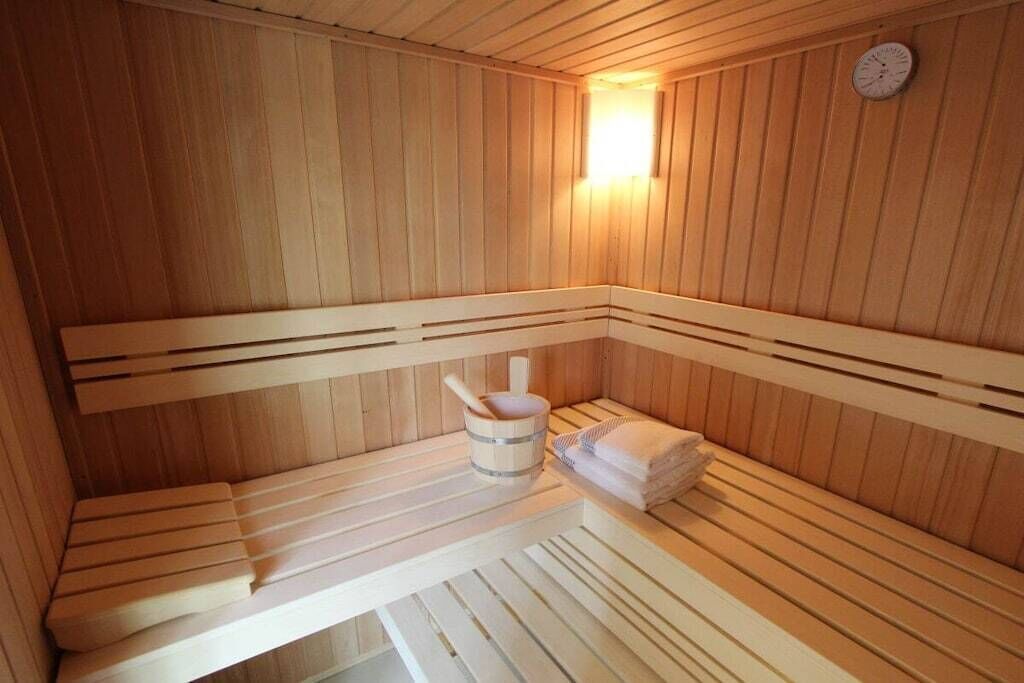 Et sauna-rum med træbænke, en spand og håndklæder.