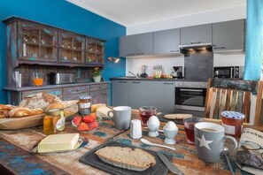 A kitchen with a blue wall, wooden cabinets, and a rustic table with food items. - Holiday apartment with 1 bedroom (Oberstdorf)
