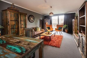 A room with a rustic wooden table, a sofa, two armchairs, a coffee table, and a large cabinet. - Holiday apartment with 1 bedroom (Oberstdorf)