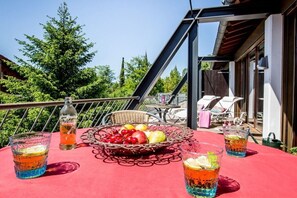 Ein Balkon mit Esstisch, einem Korbwäscher mit Obst und zwei Gläsern Getränke.