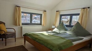 A bedroom with a bed, a chair, a window, and a radiator. - Ketterer Hinterzarten Black Forest (Hinterzarten)