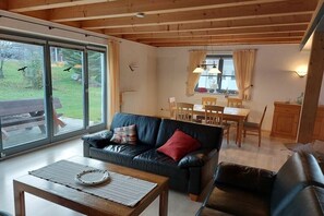 A living room with a black leather sofa, a wooden coffee table, and a dining area with a table and chairs. - Ketterer Hinterzarten Black Forest (Hinterzarten)