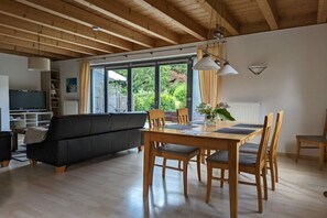 A modern living room with a sofa, dining table, and chairs. There is a television and a bookshelf. - Ketterer Hinterzarten Black Forest (Hinterzarten)