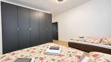 A bedroom with a large wardrobe, a bed with floral bedding, and a sofa bed.