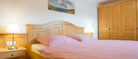 A bedroom with a wooden bed, two bedside lamps, a nightstand, and a wardrobe.