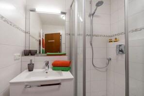 Un bagno moderno con lavandino, specchio e doccia bianchi.