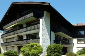 Un edificio a due piani con balconi, un pilastro in pietra e cielo sereno.
