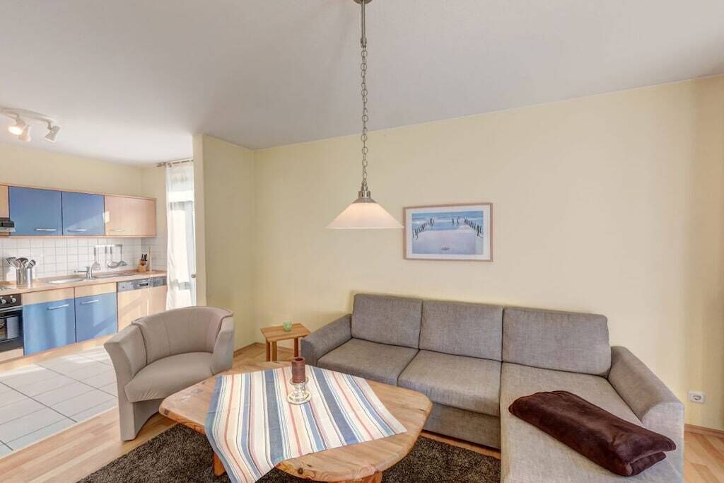 A living room with a sofa, a coffee table, and a kitchen in the background.