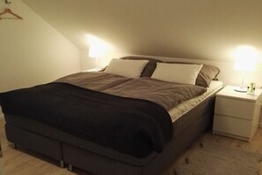 A single bed with a dark-colored headboard and footboard, flanked by two bedside tables with lamps. - Semi-detached house "LEE" (Butjadingen)
