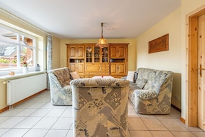 A living room with a sofa set, wooden cabinets, and a window with a view. - Laika Vacation Home in Dagebüll for up to 4 people (Dagebüll)