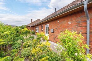 A brick house with a number '10' on the wall, surrounded by lush greenery and a clear sky. - Laika Vacation Home in Dagebüll for up to 4 people (Dagebüll)