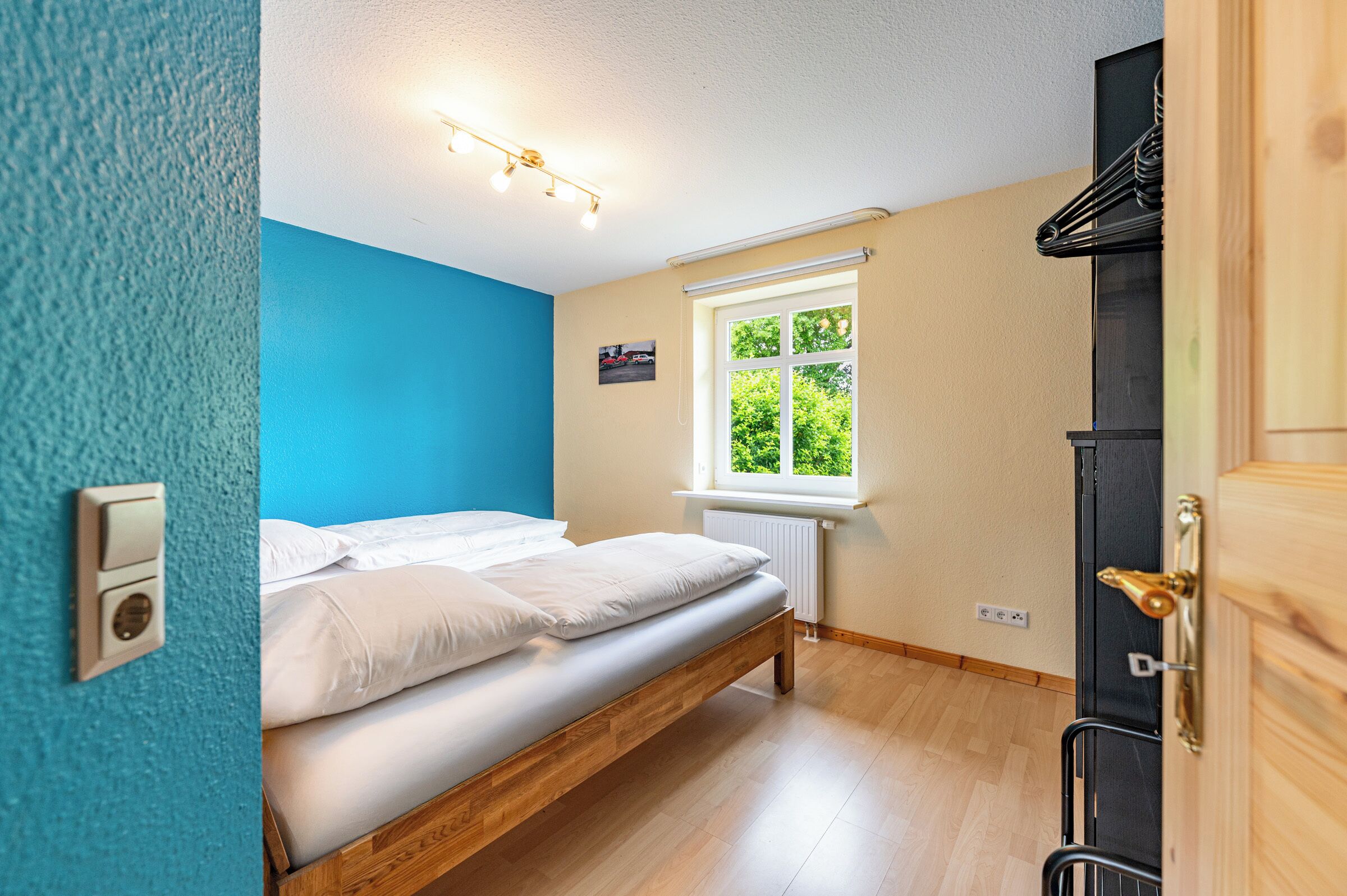 Een slaapkamer met een bed, een raam, een radiator en een deur.