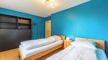 Une chambre avec deux lits, une armoire et une porte.