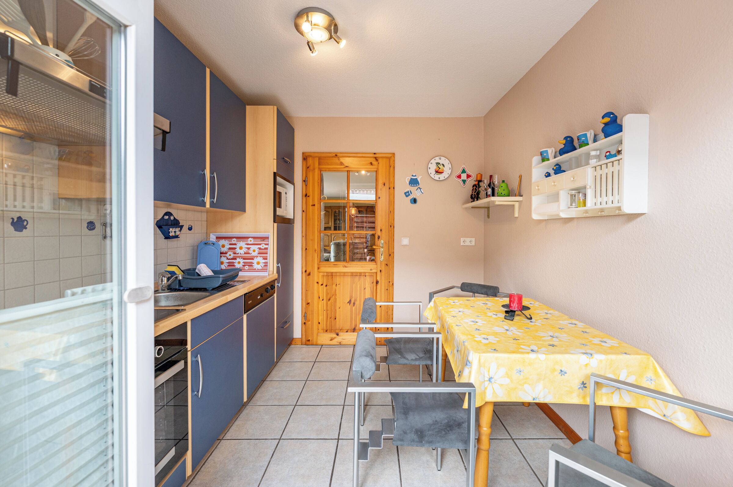 Eine kompakte Küche mit Essbereich, ausgestattet mit einer Mikrowelle, einem Herd und einer Holztür zu einem Esszimmer mit Tisch für zwei Personen.