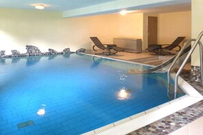 An indoor swimming pool with a tiled floor, a few lounge chairs, and a small seating area with a bench. - Holiday apartment with 2 bedrooms (Bad Hindelang)