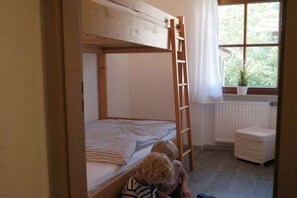 A bunk bed with a ladder, a window with a view of greenery, and a radiator. - Holiday apartment with 2 bedrooms (Bad Hindelang)