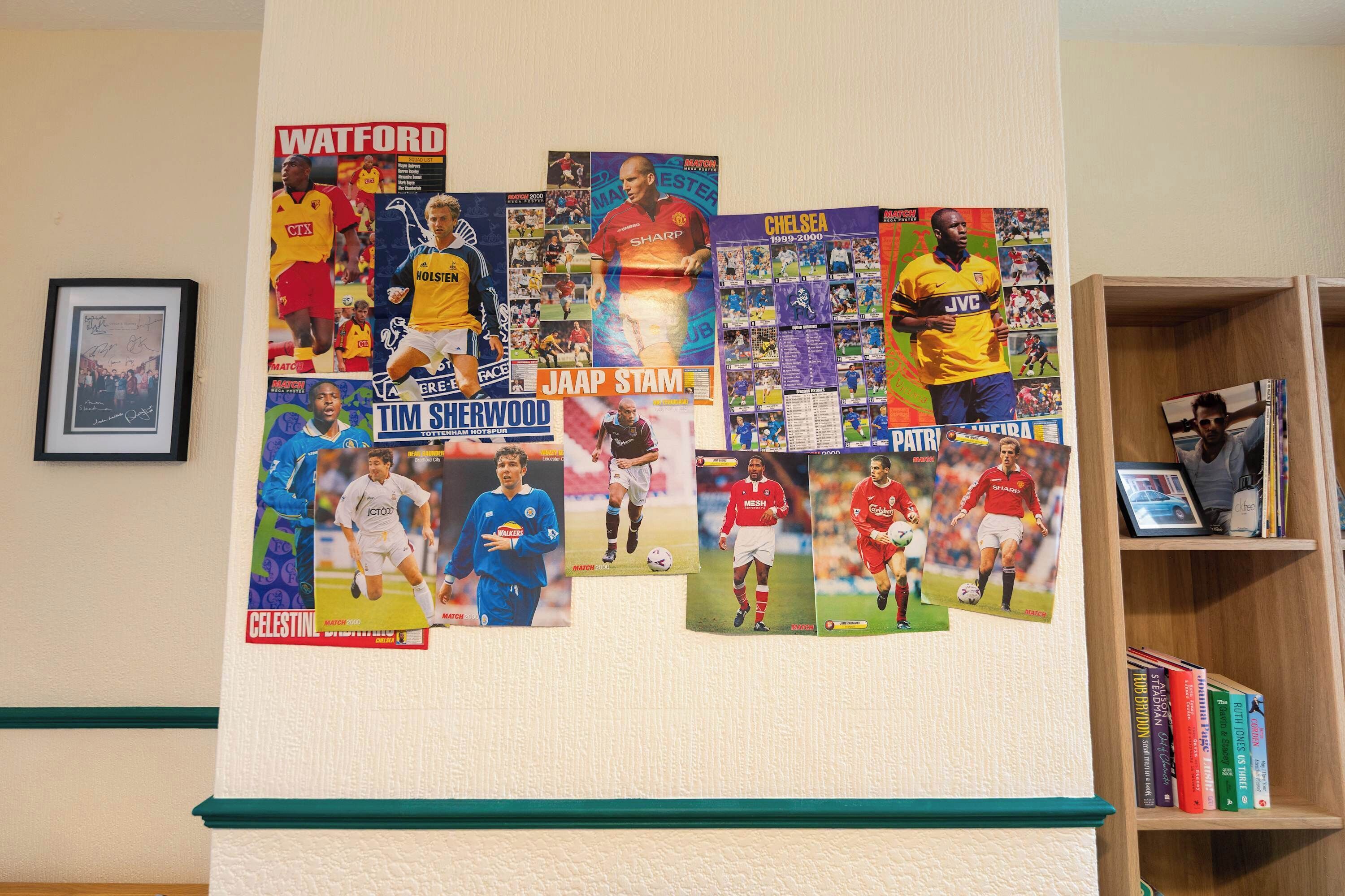 Paret amb diversos pòsters de memorabilia esportiva i una estanteria amb llibres.
