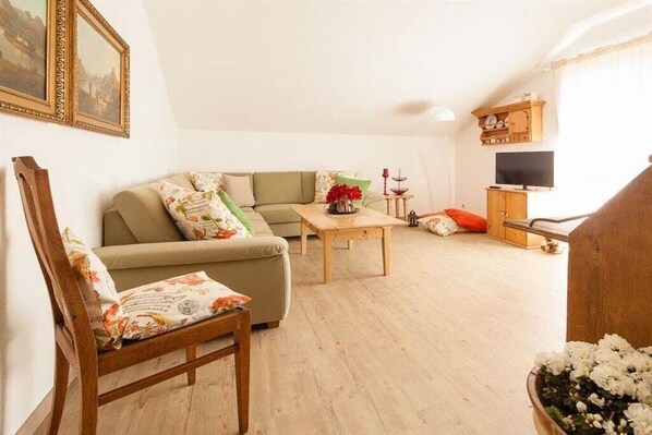 A living room with a sofa, a wooden coffee table, a television, and a cabinet.