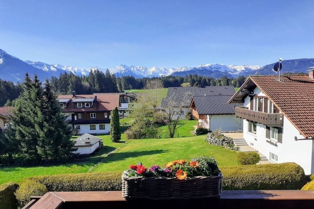 Ein Wohngebiet mit Häusern, einem Rasen und einem Bergpanorama im Hintergrund.