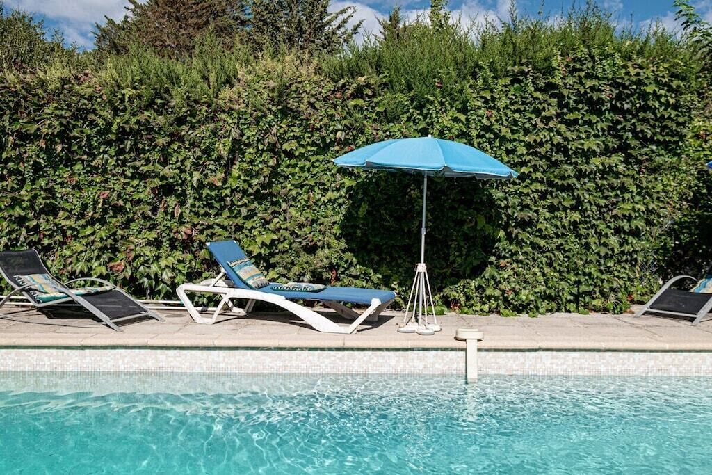 A swimming pool with lounge chairs and a blue umbrella.