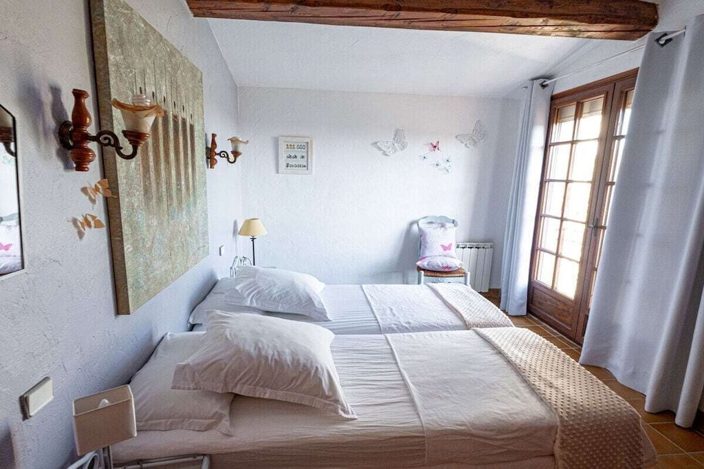 Een slaapkamer met twee bedden, een nachtkastje, een lamp en een raam met gordijnen.