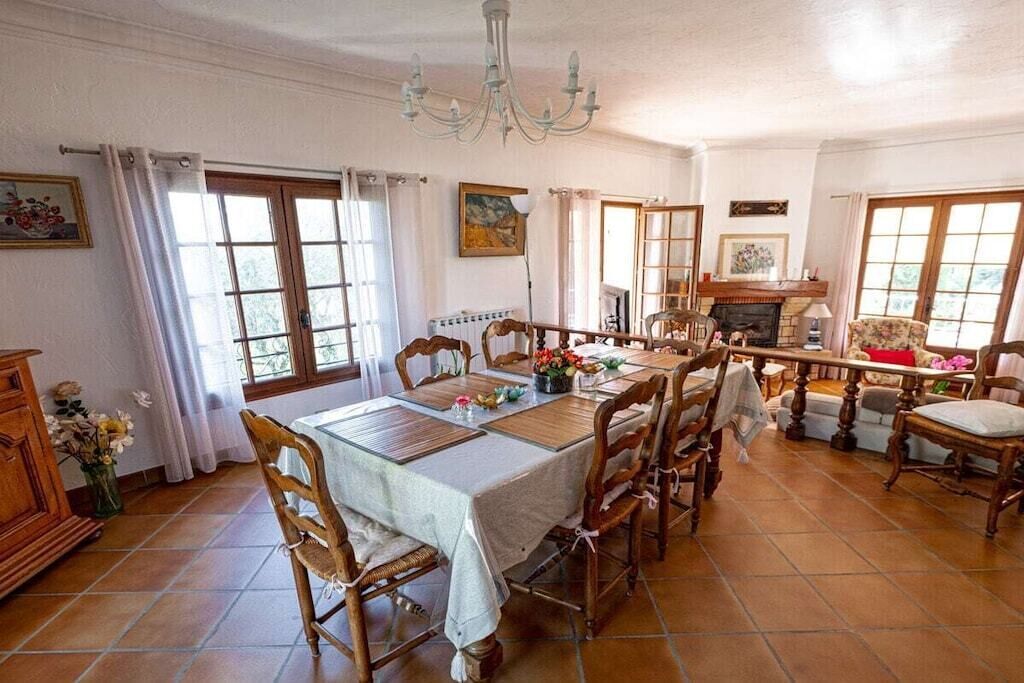 Comedor con una mesa grande, sillas, una araña y una chimenea.