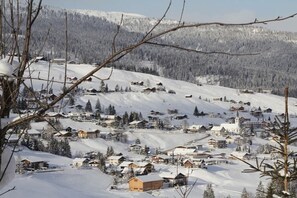 A snow-covered village with houses and a church, surrounded by mountains. - 3 in the house "Harald Heim" (Hirschegg)