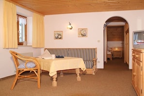 A room with a bed, a dining table, a chair, a television, and a wooden cabinet. - 3 in the house "Harald Heim" (Hirschegg)