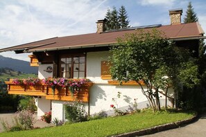 A house with a sloped roof, wooden window frames, and a balcony with flower boxes. - 3 in the house "Harald Heim" (Hirschegg)