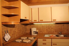 A kitchen with wooden cabinets, a coffee maker, a sink, and a stove. - 3 in the house "Harald Heim" (Hirschegg)