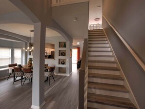 Un intérieur moderne comprenant un escalier, un coin repas et une cuisine.