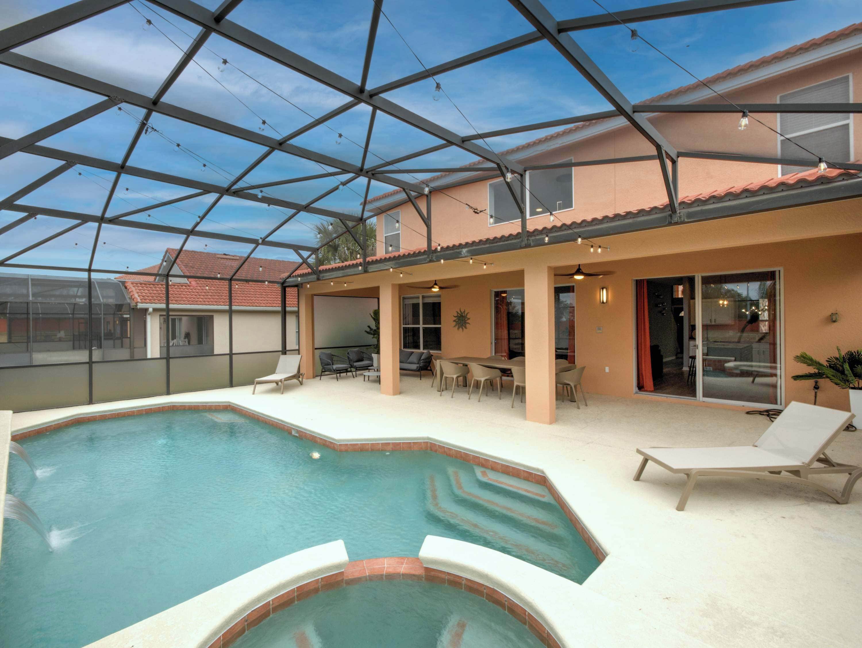 Una piscina interior con techo de vidrio, rodeada de sillones de descanso y un área de terraza.