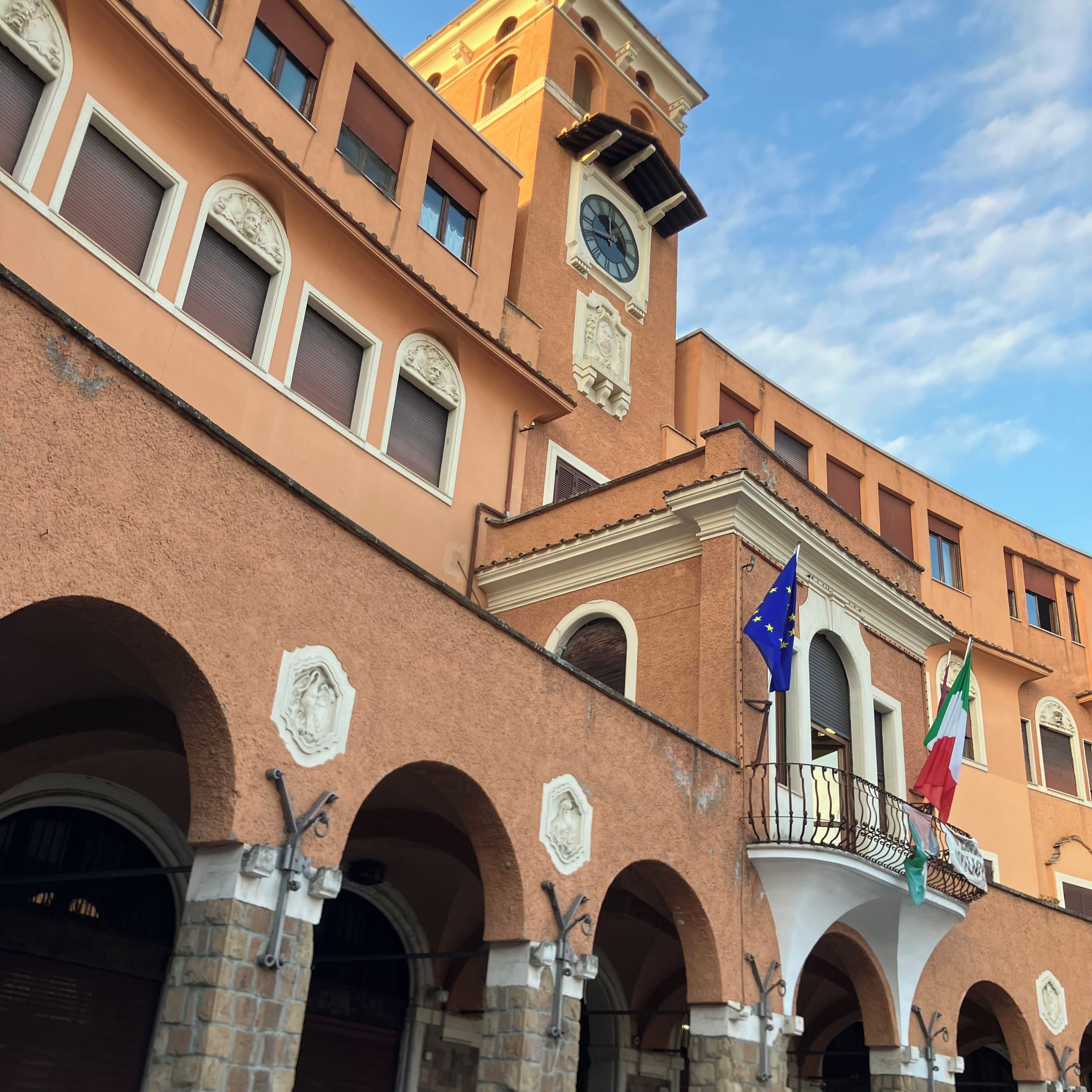 A building with multiple windows, a clock tower, and flags.