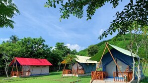 A campsite with multiple tents, each with a distinct roof color and surrounded by trees.