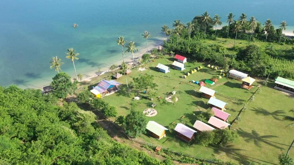 A coastal area with multiple small structures, likely accommodations, arranged in a semi-circular pattern around a beach.