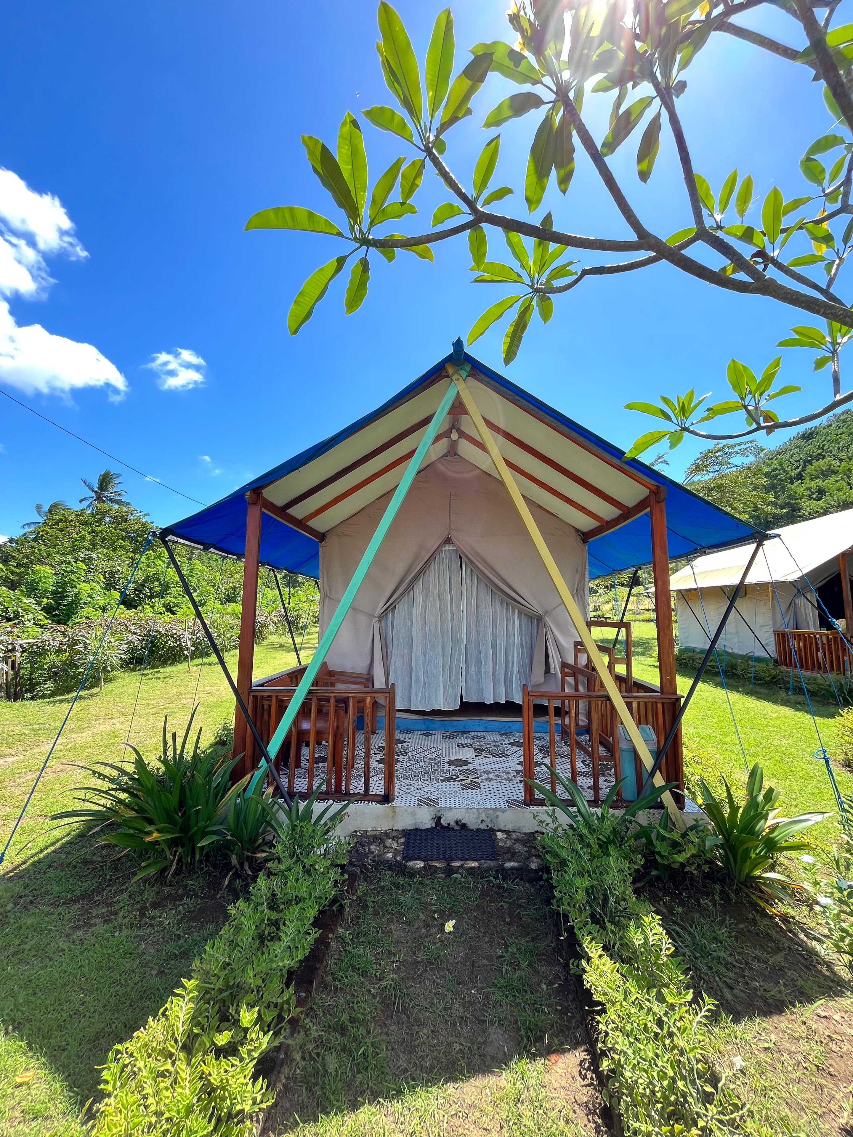 A tent with a roof supported by wooden beams and a blue canopy.