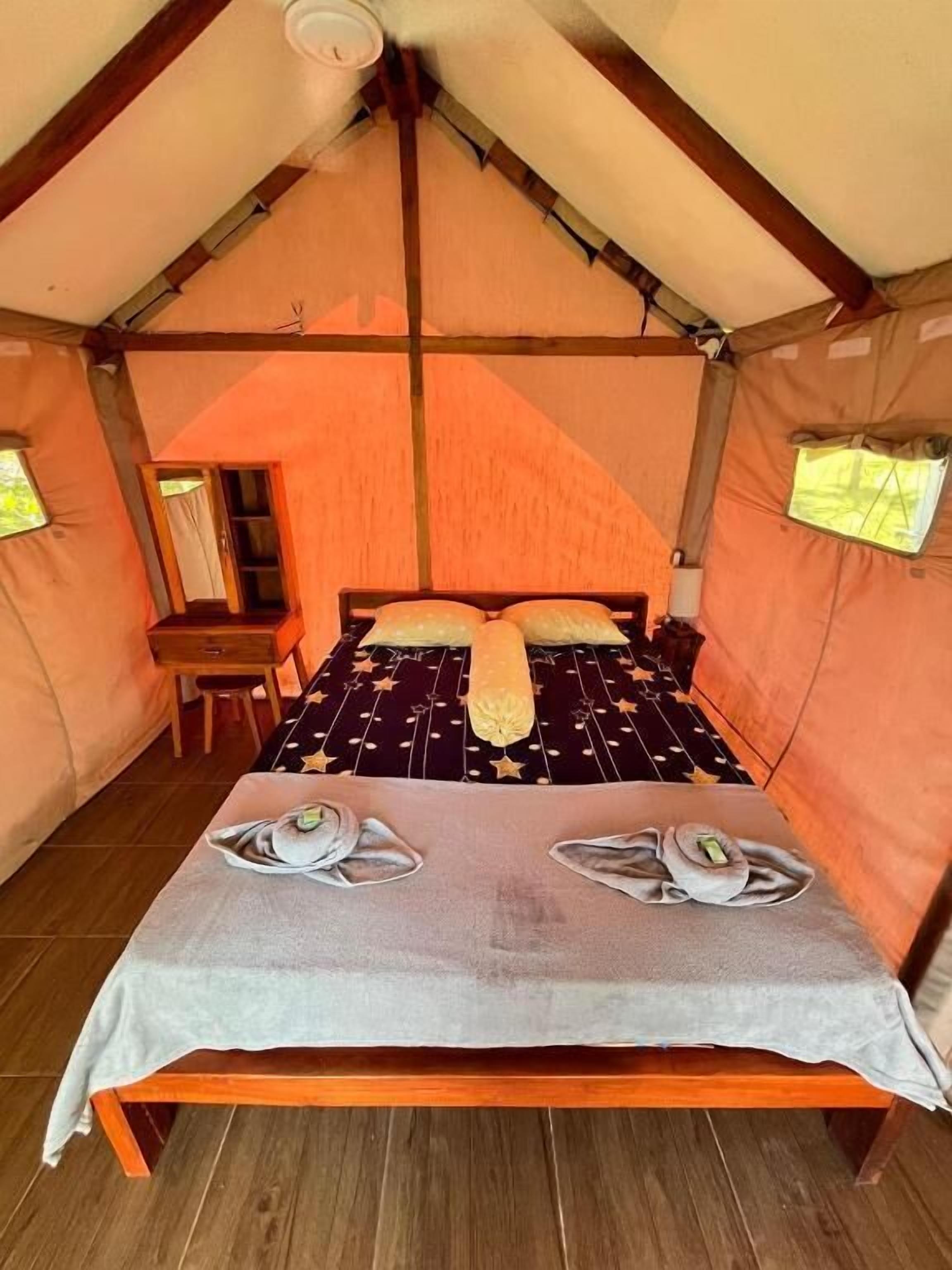Una carpa con una cama, una mesa y una silla.