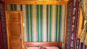 Quarto com cama, porta de madeira e parede estampada.