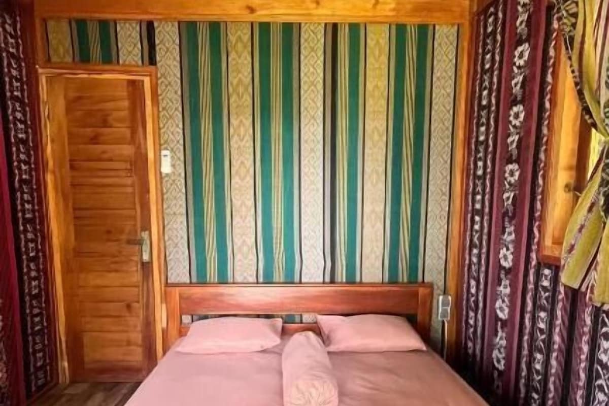 A room with a bed, a wooden door, and a patterned wall.