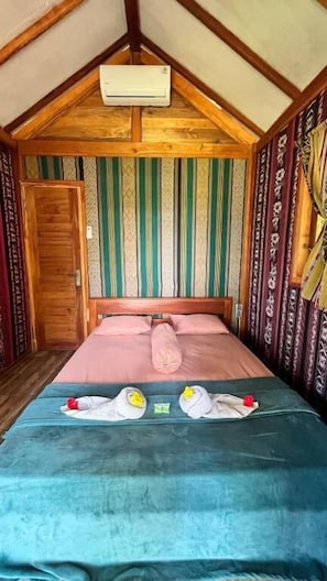 A room with a bed, a wooden door, and a patterned wall. - Beach Camp Lombok (Sekotong Barat)