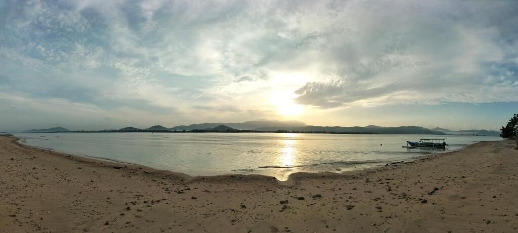 Una playa con un bote y montañas a lo lejos.