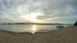 A beach with a boat and mountains in the distance.